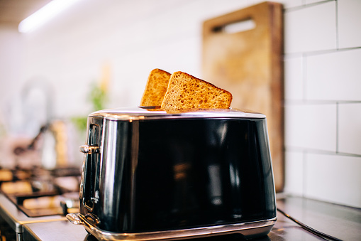 Toast popping out of black toaster in kitchen