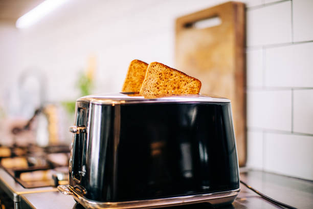 Toast ready in Toaster Toast popping out of black toaster in kitchen toaster stock pictures, royalty-free photos & images