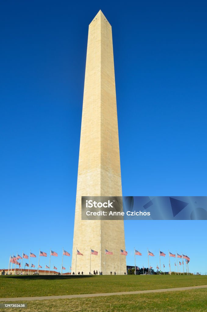 Washington Monument Against Cloudless Blue Sky Washington Monument surrounded by American flags, on a sunny day, seen against a cloudless blue sky. Washington Monument - Washington DC Stock Photo
