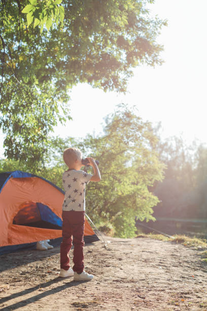 istock Happy Boy Looking Through Binoculars At Lake 1297302812
