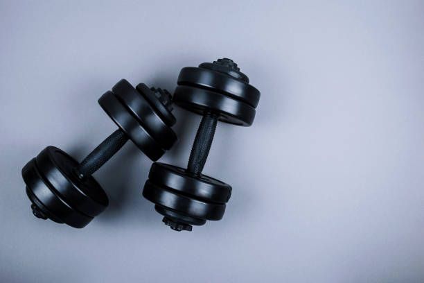 Top view of black  dumbbells  weights on pastel grey background. Flat lay.