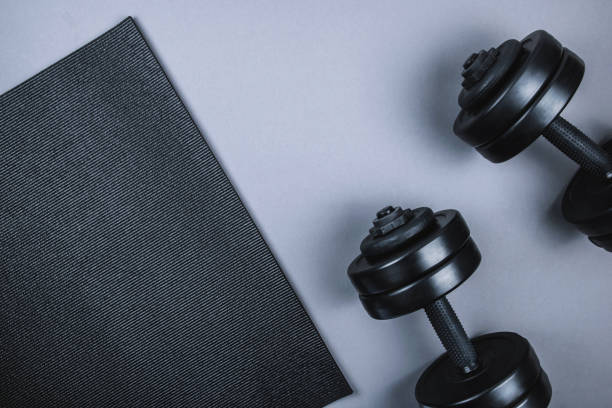 Top view of black  dumbbells  weights on pastel grey background. Flat lay. Top view of black  dumbbells weights and  mat on pastel gray background. Flat lay. Fitness or bodybuilding sport training concept. Copy space. exercise mat photos stock pictures, royalty-free photos & images