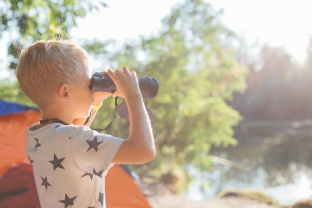 istock Happy Boy Looking Through Binoculars At Lake 1297303038