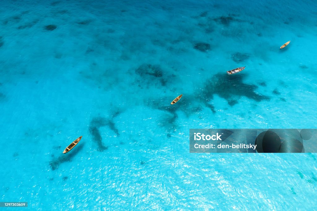 Luftaufnahme der Fischerboote in klarem blauem Wasser an sonnigen Tagen im Sommer. Top-Blick von oben des Bootes, Sandstrand. Indischer Ozean in Sansibar, Afrika. Landschaft mit Kanu und klarem Meer. reise - Lizenzfrei Afrika Stock-Foto Luftaufnahme der Fischerboote in klarem blauem Wasser an sonnigen Tagen im Sommer. Top-Blick von oben des Bootes, Sandstrand. Indischer Ozean in Sansibar, Afrika. Landschaft mit Kanu und klarem Meer. reise - Lizenzfrei Afrika Stock-Foto