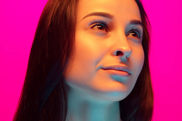 Caucasian beautiful woman's portrait isolated on pink studio background in multicolored neon light