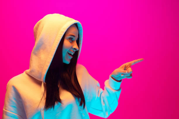 Caucasian beautiful woman's portrait isolated on pink studio background in multicolored neon light