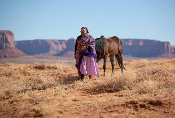 Navajo woman walking alongside her horse with protective mask during covid-19 Navajo woman walking alongside her horse with protective mask during covid-19 navajo nation covid stock pictures, royalty-free photos & images