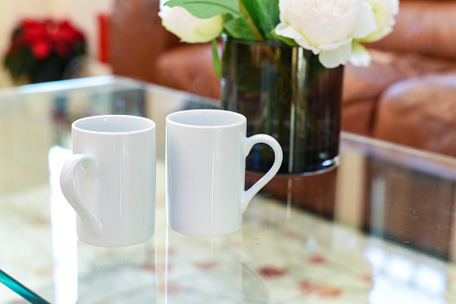 Two cups of tea or coffee together on a coffee table in a light home interior room