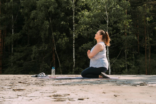 alejarse de la ciudad: mujer alegre más tamaño haciendo yoga en el bosque de la montaña - splash mountain fotografías e imágenes de stock