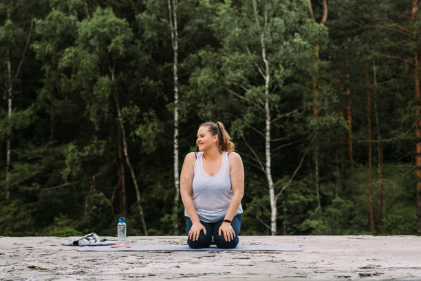 alejarse de la ciudad: mujer alegre más tamaño haciendo yoga en el bosque de la montaña - splash mountain fotografías e imágenes de stock