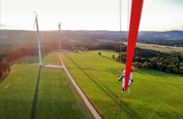 istock Epic view on Industrial climber,  rope access technician working on tip of the wind turbine blade with sunset and windfarm behind him 1297308940