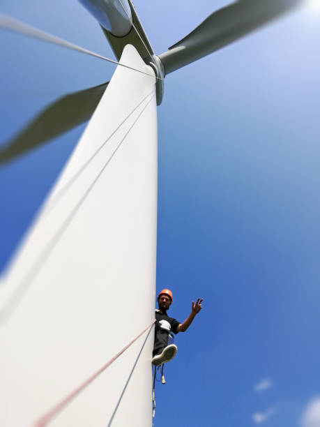 istock Low angle view on Industrial climber,  rope access technician working on gigantic onshore wind-turbine blade and performing victory gesture 1297308954