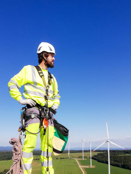 istock Industrial climber,  rope access technician standing on enormous onshore wind-turbine while preparing for blade inspection with wind farm and amazing view behind him 1297308990