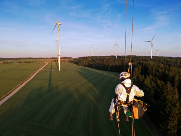 istock Areal view on Industrial climber, Rope access technicians rappelling down from wind turbine blade on the ropes in sunset, doing inspection, dramatic sky  dramatic view. 1297309000