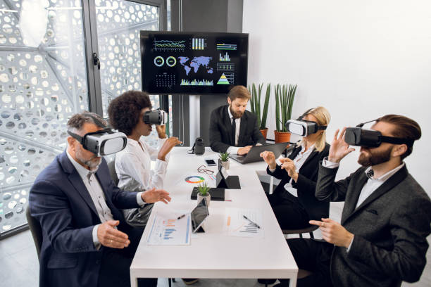 istock Business team working in vr glasses. Male boss working on laptop in office, while his multiethnic team works with virtual reality goggles and developing a project. 1297309565