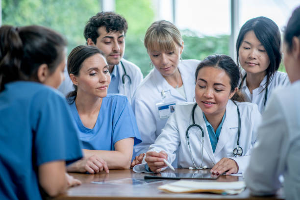 Let's take a closer look at the human anatomy A female doctor is leading a learning session for her group of medical residents at the hospital. civilian stock pictures, royalty-free photos & images