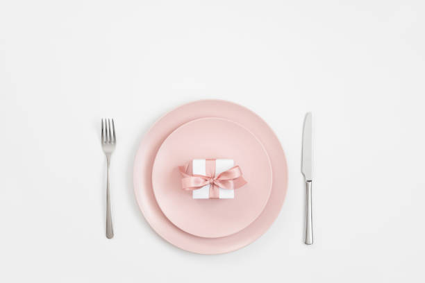 istock Gift in a pink plate on a white background. Festive table setting. Minimal concept. Space for text. View from above. Concept for Valentines or mothers day. 1297322933