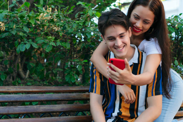 istock Happy young man with girlfriend taking a selfie at park 1297326285