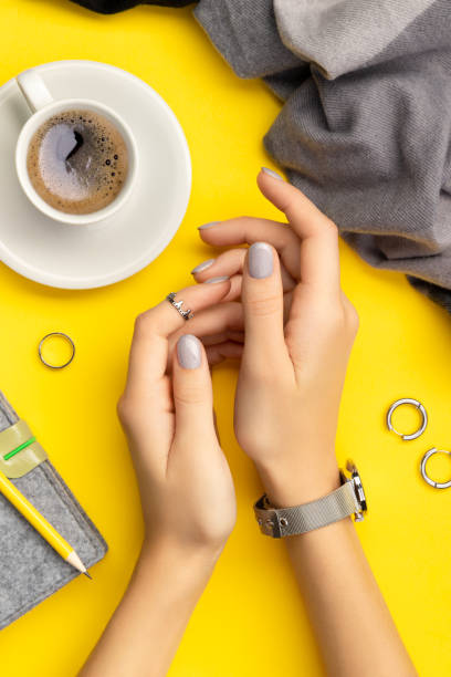 istock Womans hands with minimal manicure over yellow background 1297327164