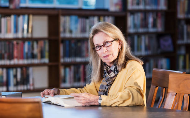 istock Senior woman in library doing research 1297334403