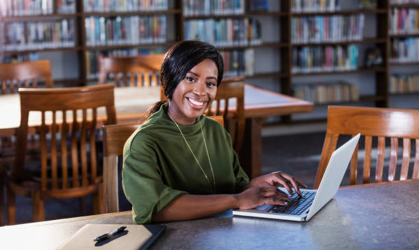 istock Young African-American woman using laptop in library 1297334437