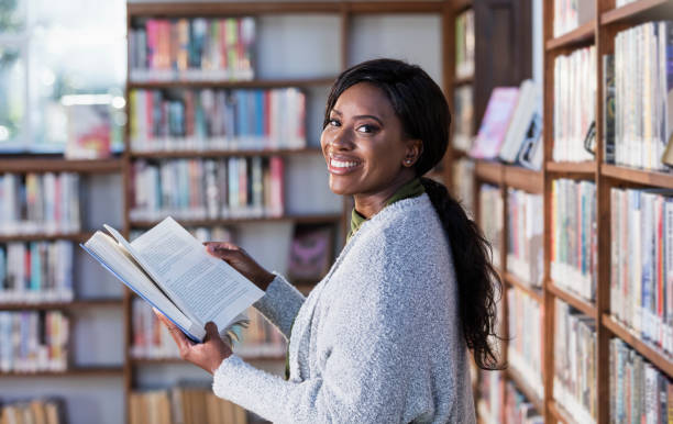 istock Young African-American woman reading in library 1297334475