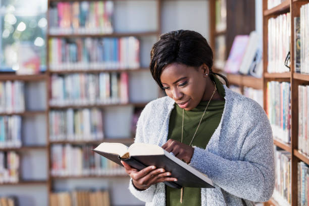 istock Young African-American woman reading in library 1297334485