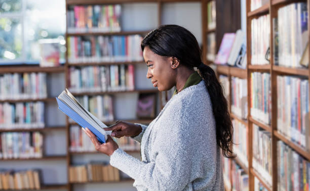 istock Young African-American woman reading in library 1297334504