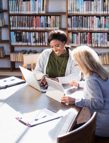 istock Two women with laptops working together in library 1297334509
