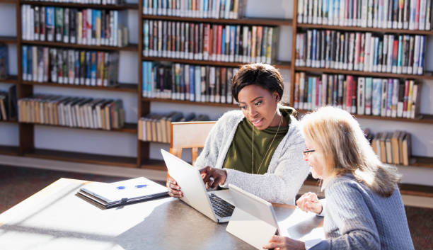 istock Two women with laptops working together in library 1297334533