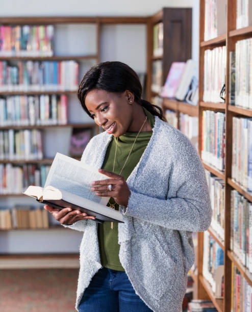 istock Young African-American woman reading in library 1297334539
