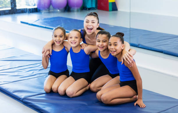 тренер по гимнастике с четырьмя девушками в тренажерном зале - gymnastics стоковые фото и изображения