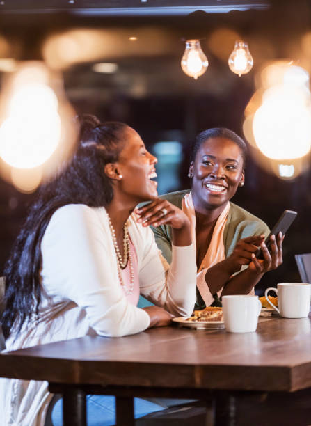 istock Two friends laughing while looking at mobile phone 1297335459