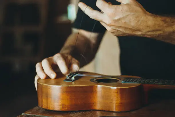 Photo of Tuning the string of ukelele, human hands, closeup