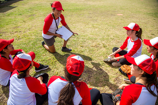 Sports, baseball and coach talking to the team on the field before a game, workout or training. Fitness, discussion and trainer planning a strategy with a male sport group before a match or practice.