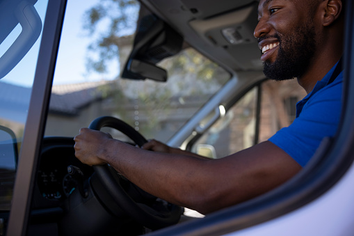 An African American man making deliveries from his cargo van on a sunny day.