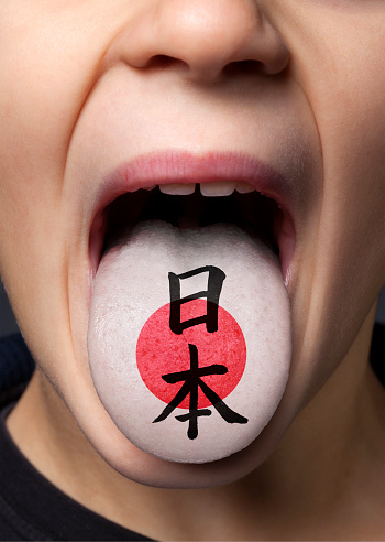 Little boy sticking out his tongue with painted Japanese flag.