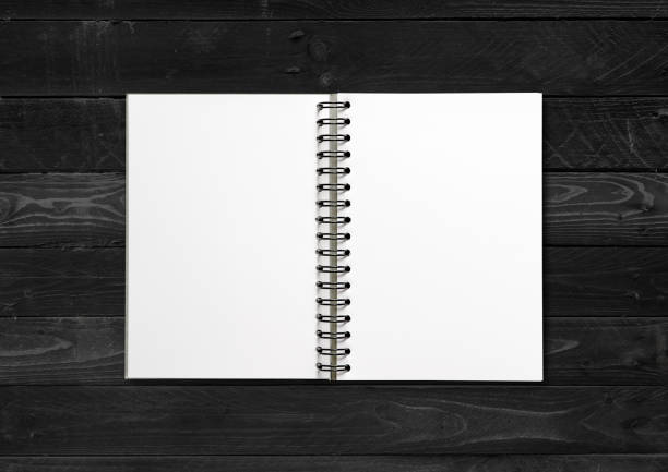 istock Blank open spiral notebook isolated on black wood background 1297358860