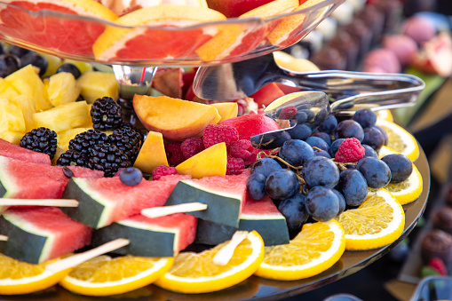 Fruit buffet on cakestand with watermelon, peach and orange slices, berries and grapes
