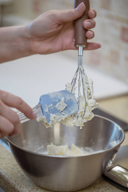 istock Female hands hold a whisk with whipped cream. 1297360156
