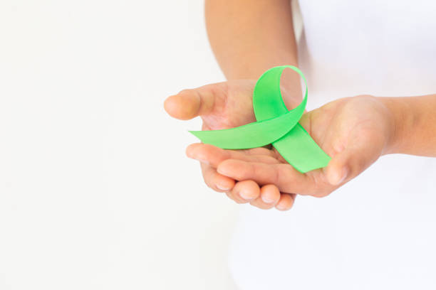 istock Hands holding emerald green or jade green ribbon on white fabric background with copy space, symbol for Liver Cancer awareness, World Cancer Day. Healthcare or hospital and insurance concept. 1297360784