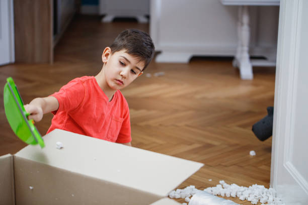 istock Boy scooping packing peanut with shovel and pouring in box 1297361857