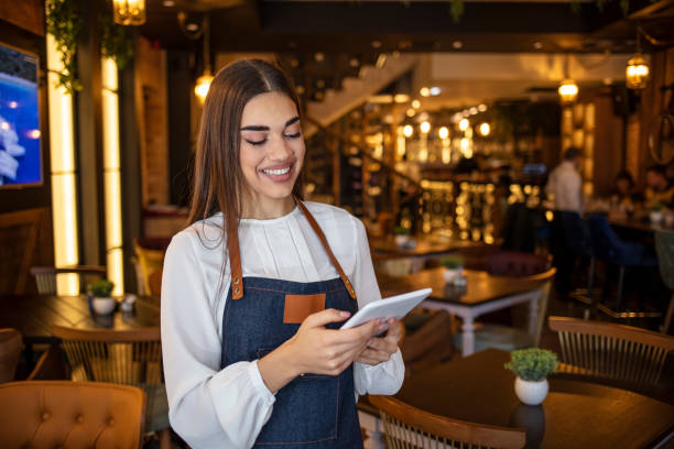 istock Young beautiful girl in denim apron in a coffee shop, working on a computer. 1297364096