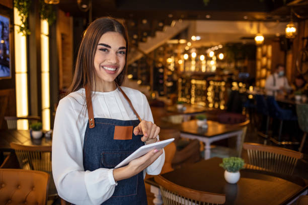 istock Portrait of a happy waitress working at a restaurant using a tablet computer and smiling 1297364116
