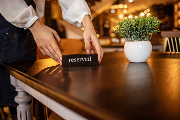 Elegant Restaurant Table Setting Service for Reception with Reserved Card Restaurant Chilling Out Classy Lifestyle Reserved Concept. Waitress reserving a tablet at a restaurant and putting a sign on the table - food service concepts exclusive dinner stock pictures, royalty-free photos & images