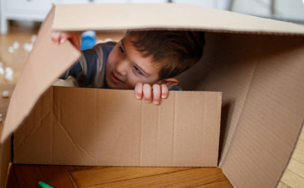 istock Smiling toddler lying in empty box on the floor during house move 1297364233
