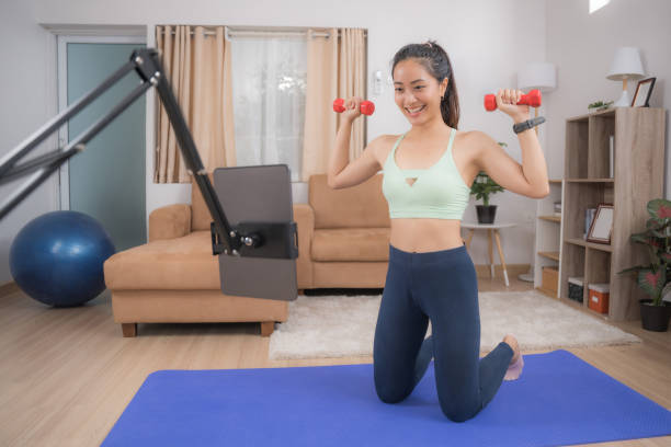 istock Asian woman exercising at home, she is watching online tutor. 1297369030
