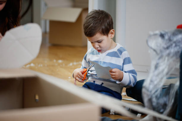 istock Toddler sitting on messy floor focused on cutting paper with scissors 1297369513