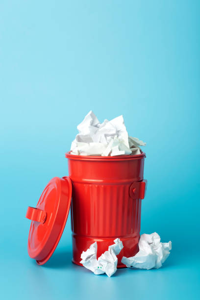 istock Paper trash and waste in a trash bin on a blue background. Waste and paper sorting and recycling concept 1297370891