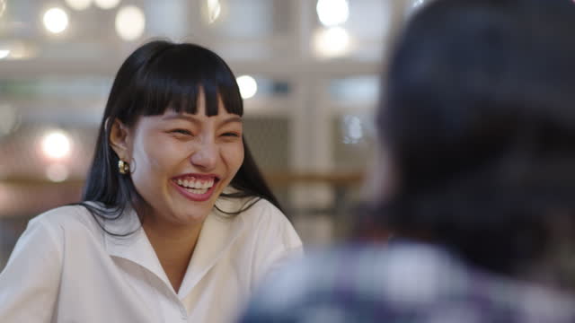 Close up asian woman talking and listening. Happy asia girl conversation with friend in dinner party. Smile young woman discussion, listen and sharing news gossiping telling funny story.